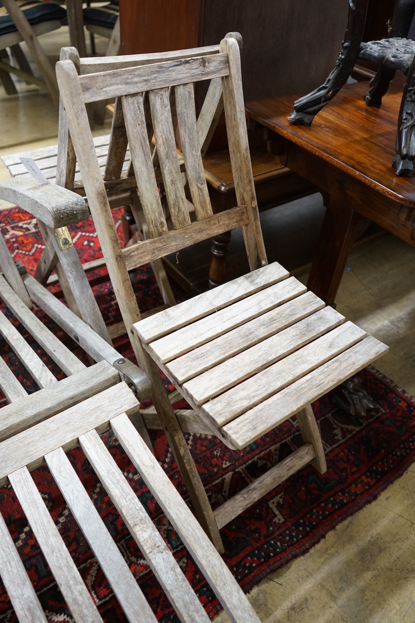 A weathered teak garden steamer chair and two folding garden chairs